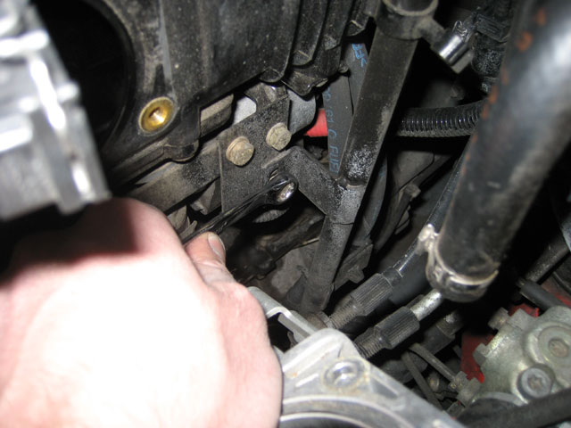 Unbolting the oil dipstick tube to remove the intake manifold.